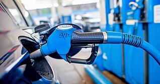 Eine Zapfpistole mit der Aufschrift &bdquo;Super 95&ldquo; steckt an einer Tankstelle in der Tank&ouml;ffnung eines Fahrzeugs.