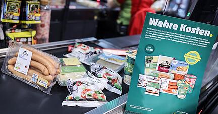 Produkte deren Preis mit den verdeckte Kosten angepasst wurden, liegen an der Kasse.
