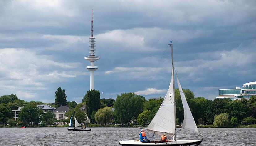 Dunkle Wolken ziehen über den Fernsehturm und die Außenalster, auf der Segelboote kreuzen. Dunkle Wolken ziehen über den Fernsehturm und die Außenalster, auf der Segelboote kreuzen.