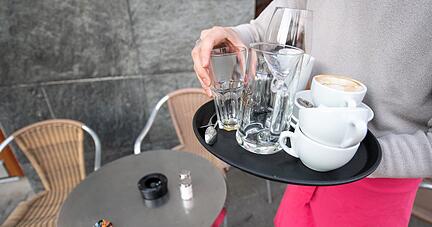 Ein Kellner räumt einen Tisch in einem Restaurant ab.
