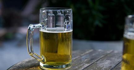 Zwei Bierkr&uuml;ge stehen in einem Biergarten auf einem Tisch.