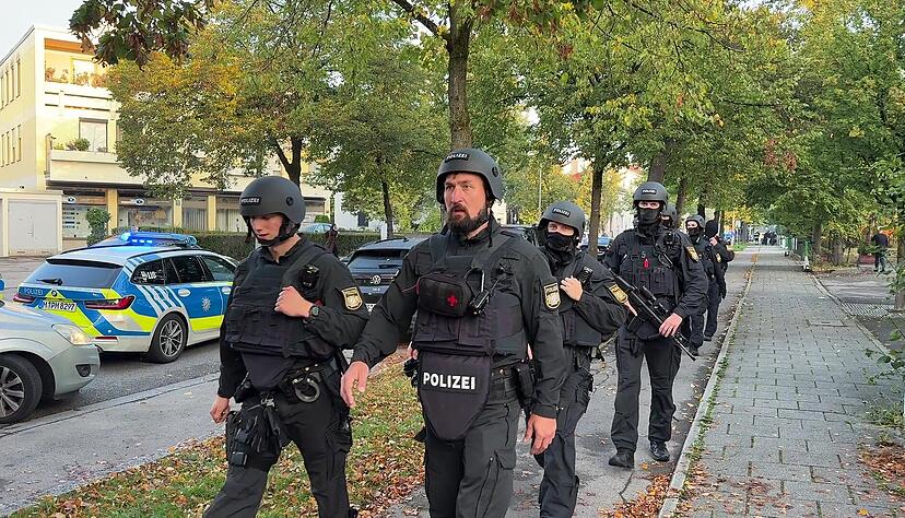 Polizisten mit Schutzwesten sind nach einem Brand in einem Münchner Einfamilienhaus im Einsatz. Es soll zu Explosionen gekommen sein.