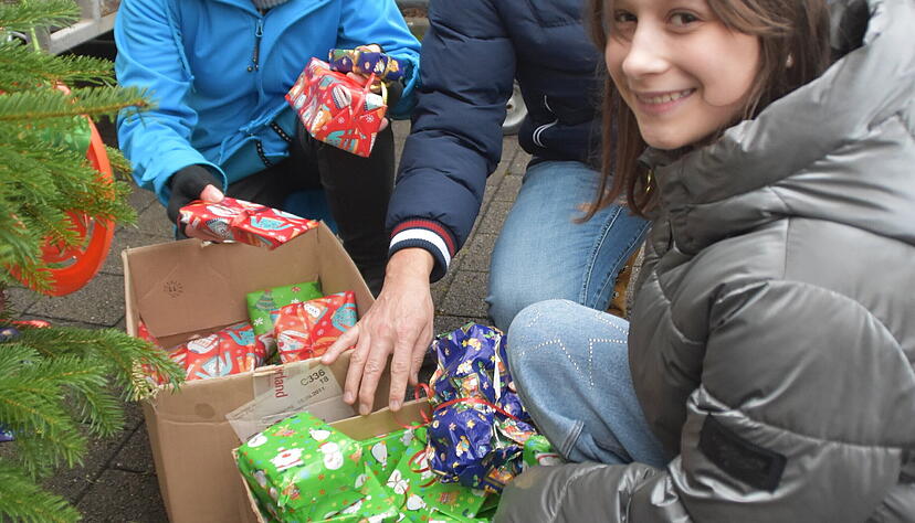 Maida und Denis Solka (von rechts) suchen sich mit Angelika Merz vom F&ouml;rderverein f&uuml;r krebskranke Kinder T&uuml;bingen am &bdquo;Baum der guten Tat&ldquo; ein sch&ouml;nes P&auml;ckchen aus. F&uuml;r eine Spende an den Verein erhalten die beiden eine echte &Uuml;berraschung, die vielleicht unter dem eigenen Tannenbaum landet.