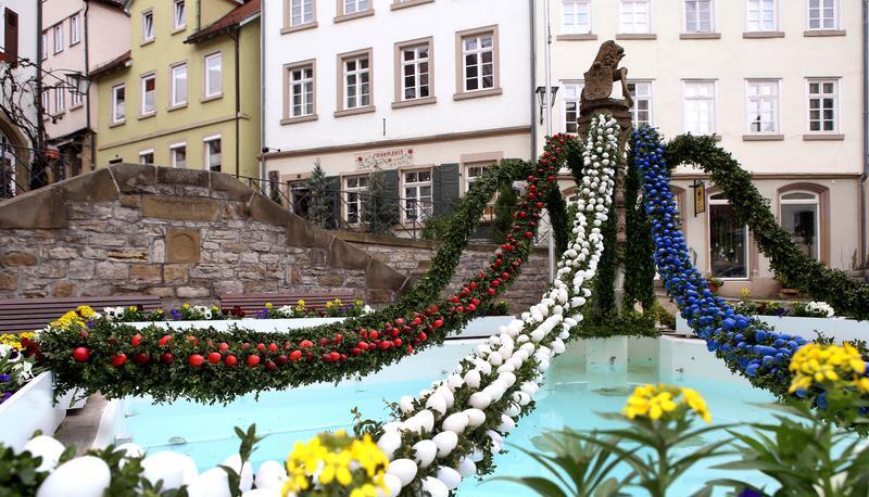 In den Farben der Stadt: Der L&ouml;wenbrunnen pr&auml;sentiert sich in Rot, Wei&szlig; und Blau. Lila Stiefm&uuml;tterchen und gelber Goldlack setzen bunte Akzente.