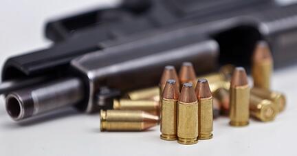 Eine Faustfeuerwaffe liegt mit Magazin und Munition auf einem Tisch.