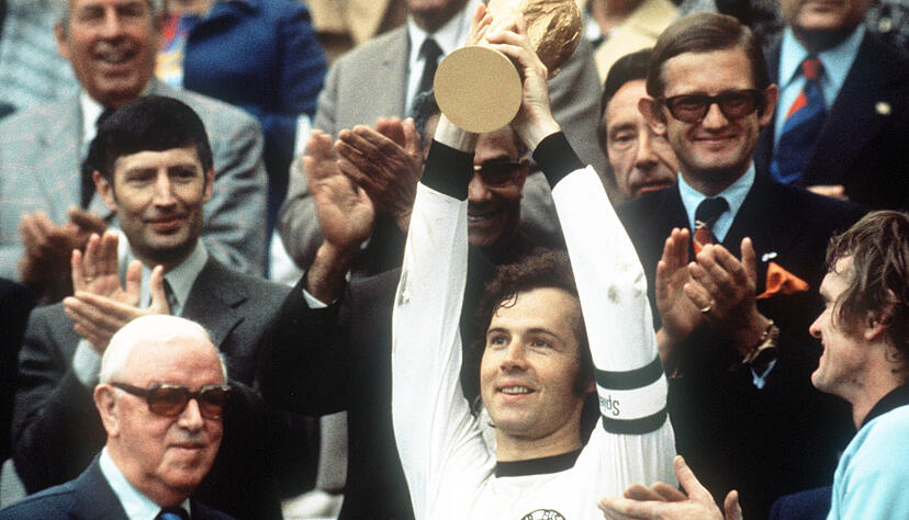 Kapitän Franz Beckenbauer (M) hebt an der Seite von Torhüter Sepp Maier (r) und dem englischen FIFA-Präsidenten Stanley Rous (l) im Olympiastadion nach dem Endspiel der Fußball-WM den eroberten WM-Pokal hoch. Kapitän Franz Beckenbauer (M) hebt an der Seite von Torhüter Sepp Maier (r) und dem englischen FIFA-Präsidenten Stanley Rous (l) im Olympiastadion nach dem Endspiel der Fußball-WM den eroberten WM-Pokal hoch.