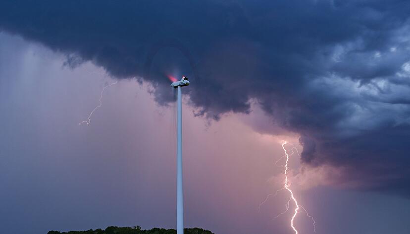 Ein Blitz leuchtet am Abendhimmel hinter einer Windenergieanlage im Osten Brandenburgs.