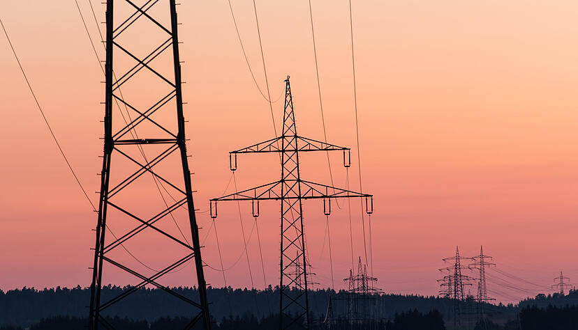 Strommasten sind bei Sonnenaufgang als Silhouette zu sehen. +++ dpa-Bildfunk +++