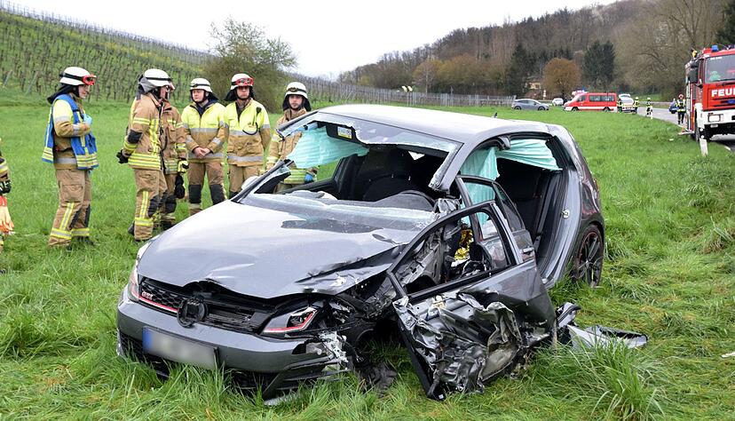 Einsatkräfte der Feuerwehr stehen neben einem Unfallfahrzeug an der Kreisstraße K4170. Ein junger Autofahrer ist bei einem Zusammenprall mit einem Auto auf einer Kreisstraße in Dielheim (Rhein-Neckar-Kreis) schwer verletzt worden.