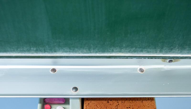 Schwamm und Kreide liegen in einem Klassenraum unter einer Tafel. Schwamm und Kreide liegen in einem Klassenraum unter einer Tafel.