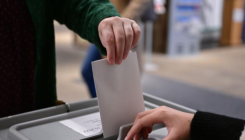 Ein Wähler steckt bei einer Wahl seinen Wahlzettel in eine Urne.