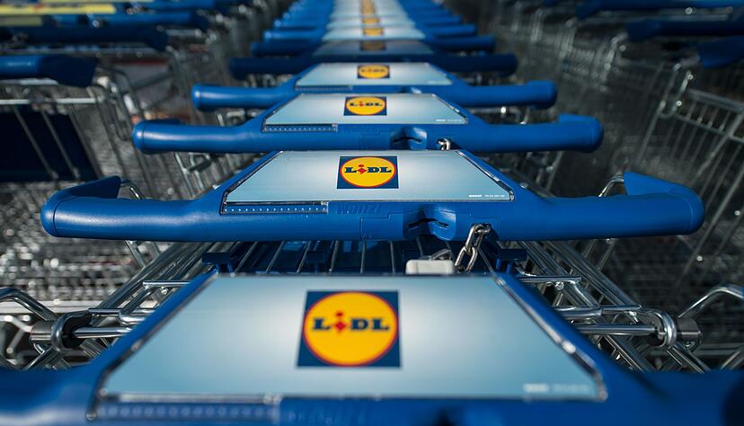 Einkaufswagen stehen vor einer Filiale des Lebensmitteldiscounters Lidl.
