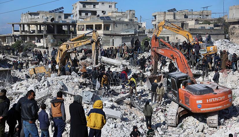 Rettungskräfte und Anwohner durchsuchen die Trümmer eingestürzter Gebäude nach Überlebenden.