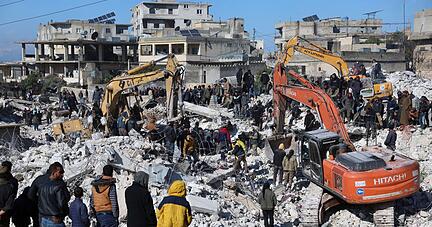 Rettungskräfte und Anwohner durchsuchen die Trümmer eingestürzter Gebäude nach Überlebenden.