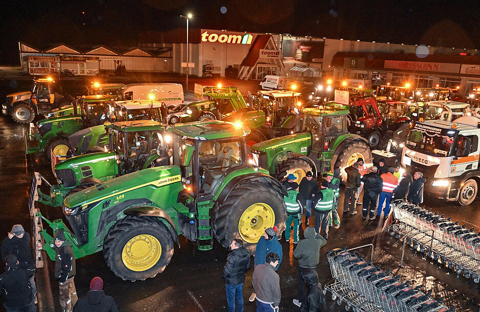 Viele Traktoren von Landwirten stehen am frühen Morgen auf einem Parkplatz, um sich für ihre Fahrt in Richtung Berlin zu sammeln.