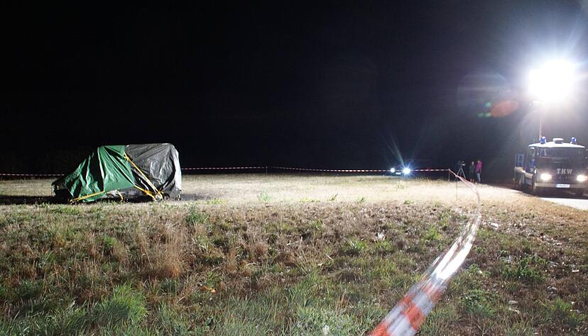 Ein ausgebranntes und in Planen gehülltes Wohnmobil steht auf einer Wiese. Zwei Menschen wurden in dem Fahrzeug tot aufgefunden. Foto: dpa