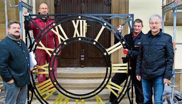 J&uuml;rgen Brame (links) und Pfarrer Eberhard Theilig (rechts) mit Monteuren der Turmuhren-Firma und dem 80 Kilogramm schweren Skelett-Ziffernblatt.Foto: Staudinger