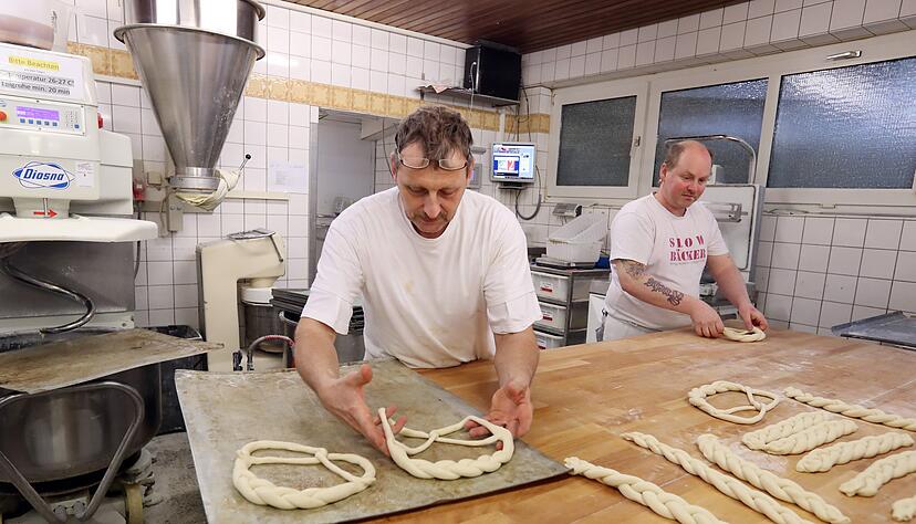 B&auml;cker Roland Vogt legt die Neujahrsbrezeln auf ein Blech, das er vorher mit Fett eingespr&uuml;ht hat. &Uuml;ber Nacht kommen die Brezeln ins K&uuml;hlhaus. Rechts sein Kollege Andr&eacute; De La Veaux.
Fotos: Andreas Veigel