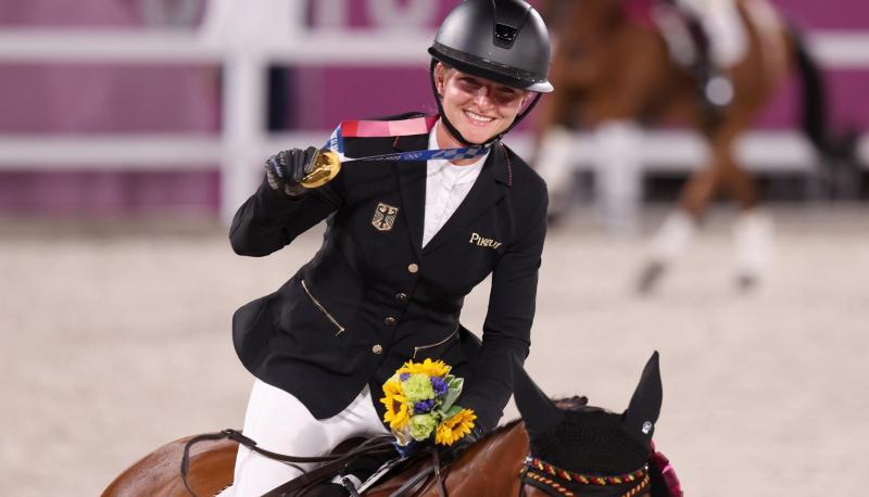 Mit der Goldmedaille um den Hals reitet Julia Krajewski nach der Siegerehrung auf Amande de B`Neville eine Ehrenrunde. Mit der Goldmedaille um den Hals reitet Julia Krajewski nach der Siegerehrung auf Amande de B`Neville eine Ehrenrunde.