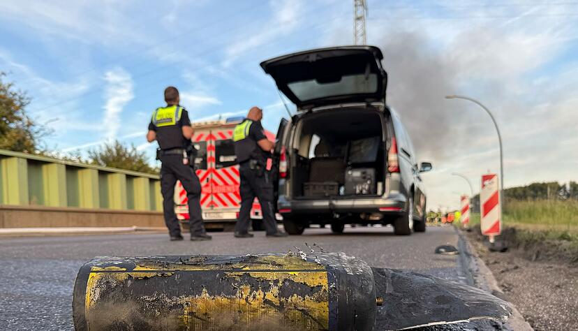 Polizisten stehen hinter einem Metallbeh&auml;lter. Tr&uuml;mmerteile sollen bei dem Brand Hunderte Meter weit geflogen sein.