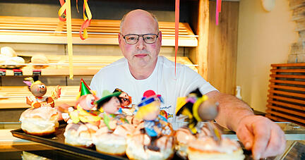 Bäcker Ralf Herrmann hält in seiner Bäckerei ein Blech mit dekorierten Faschingskrapfen in den Händen. Der Heilbronner Bäcker, dessen dekorierte Berliner die Antidiskriminierungsstelle teils als stigmatisierend kritisiert, will die figürlichen Pappstecker weiter verwenden.
