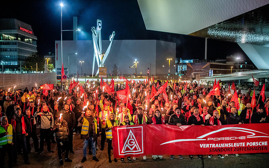 Mitarbeiter von Porsche nehmen vor dem Werk in Stuttgart-Zuffenhausen mit Fahnen am Warnstreik der IG Metall teil.