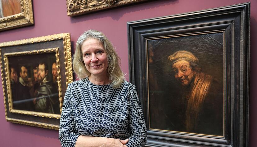 Anja Sevcik steht zwischen einem Selbstbildnis von Peter Paul Rubens unter Freunden (links) und einem Selbstbildnis von Rembrandt (rechts).
