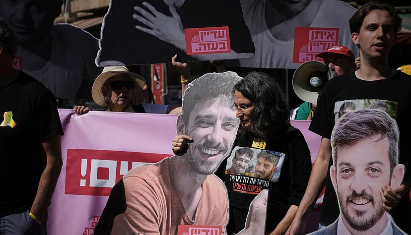 Demonstranten halten bei einem Protest gegen die Offensive in der Stadt Gaza Fotos von Geiseln.