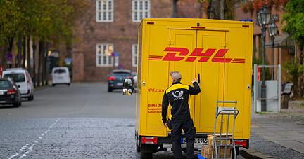 Ein Zusteller entl&auml;dt ein Fahrzeug von DHL in L&uuml;neburg.