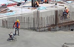 Beton ist empfindlich: Arbeiter sorgen für eine glatte Oberfläche und benetzen sie mit Wasser, um Risse zu vermeiden. Beton ist empfindlich: Arbeiter sorgen für eine glatte Oberfläche und benetzen sie mit Wasser, um Risse zu vermeiden.