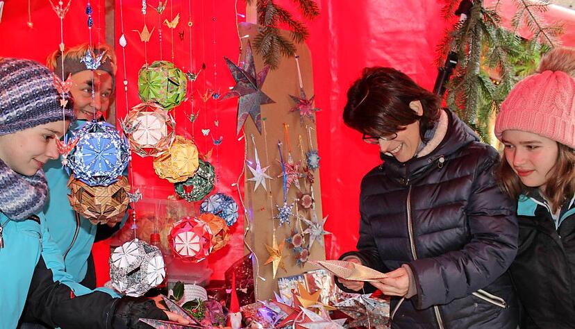 Olivia und Petra Romeiks (Zweite von rechts) gefallen die Papiersterne und Kugeln am Stand von Simone und Daniela Bauer.Foto: Regina Koppenhöfer