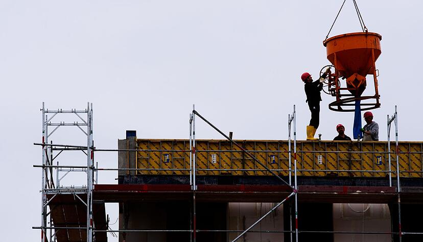 Arbeiter stehen auf einer Baustelle eines Wohngeb&auml;udes.