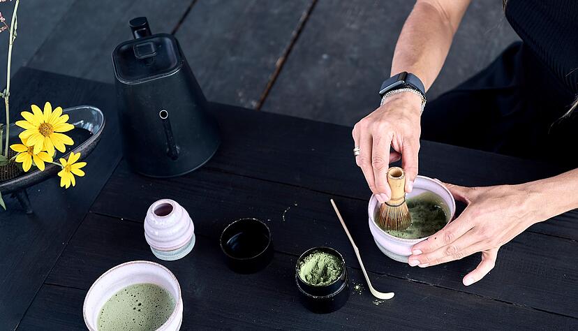 Das Matcha-Pulver wird mit Wasser und einem Besen schaumig geschlagen. Das Matcha-Pulver wird mit Wasser und einem Besen schaumig geschlagen.