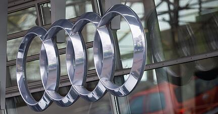 Das Logo von Audi h&auml;ngt an der Fassade eines Audi-H&auml;ndlers.