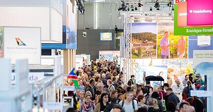 Besucher gehen während der Reisemesse CMT durch eine Halle.