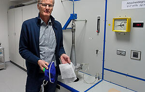 Laborleiter Reinhard Wierling vor dem Pr&uuml;fstand, auf dem man nachweisen kann, wie viele Mikro-Partikel ein Filterstoff zur&uuml;ckh&auml;lt.