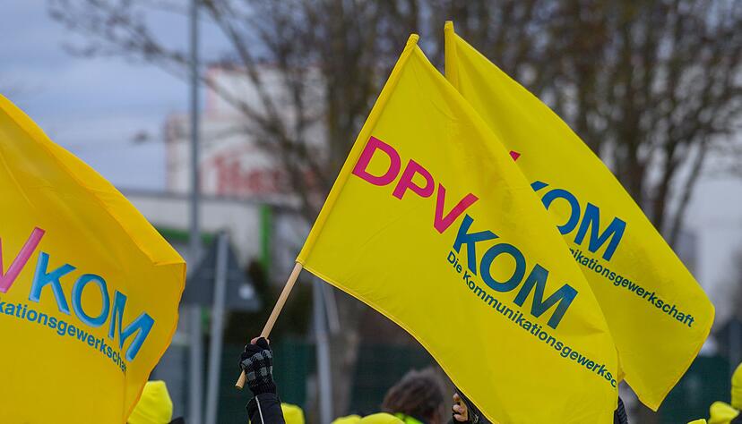 Warnstreikende schwenken vor dem DHL Paketzentrum Osterweddingen (Sachsen-Anhalt) Fahnen der Gewerkschaft DPVKOM. Nun ruft die Gewerkschaft zu Warnstreiks im Raum Karlsruhe auf. Warnstreikende schwenken vor dem DHL Paketzentrum Osterweddingen (Sachsen-Anhalt) Fahnen der Gewerkschaft DPVKOM. Nun ruft die Gewerkschaft zu Warnstreiks im Raum Karlsruhe auf.