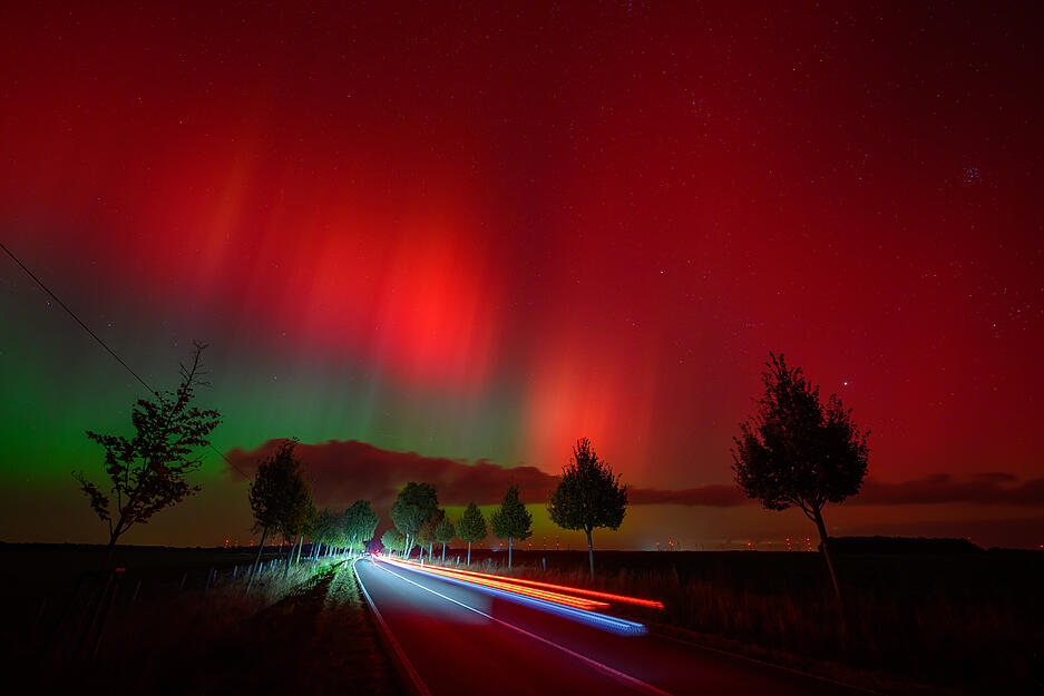 Polarlichter leuchten am Nachthimmel über einer Straße im östlichen Brandenburg.